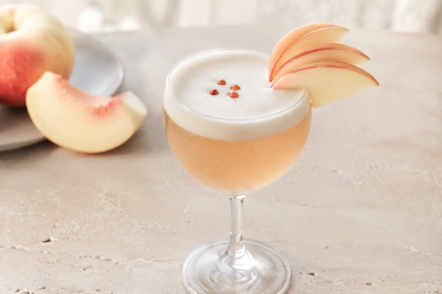 Alcohol-free white peach and chamomile sour with aquafaba foam in a chilled Nick and Nora glass