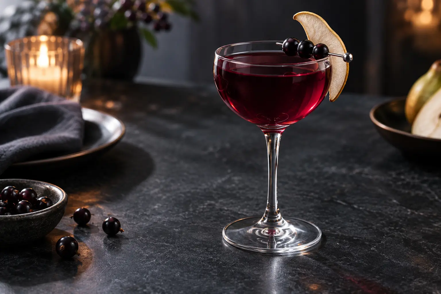 Alcohol-free blackcurrant juniper mocktail with pear chip and blackcurrant garnish in a chilled Nick and Nora glass